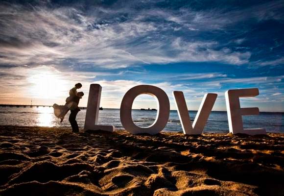 Bride and groom in the sunset at Brighton Beach next to letters which spell LOVE